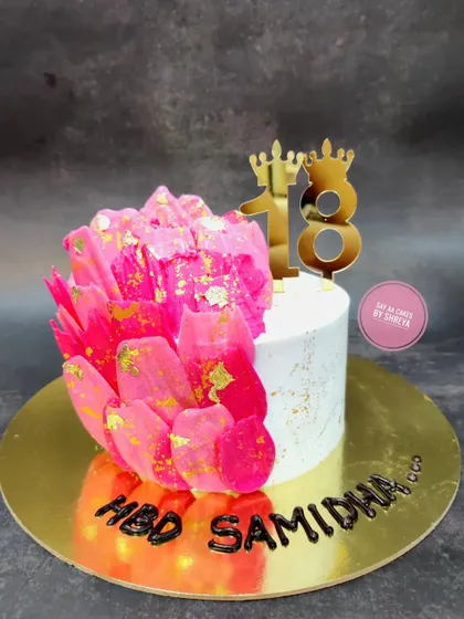 A vibrant and modern cake to celebrate an 18th birthday. The striking pink rice paper sail and gold leaf accents create a dramatic and stylish look for this important milestone.