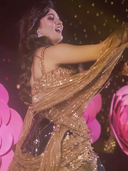 A close-up shot capturing the bride's radiant energy during her dance. The stage was decorated with giant paper flowers to create a vibrant, floral-themed backdrop for her performance.