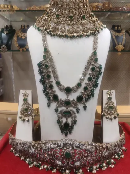 A complete Victorian bridal set with rich emerald green stones, including a choker, layered haram, and a matching vaddanam.