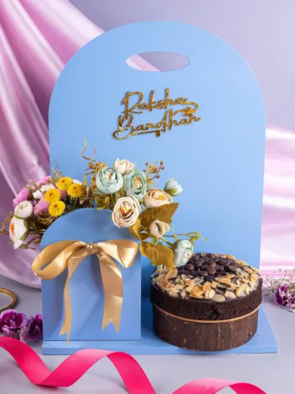 An innovative Raksha Bandhan hamper design, featuring a cake and floral arrangement in a unique, modern carrier.