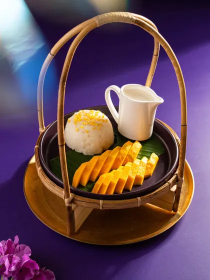 A classic Thai dessert, mango with sticky rice, from Nara Thai. The dish is presented in a traditional bamboo carrier, adding an authentic touch.