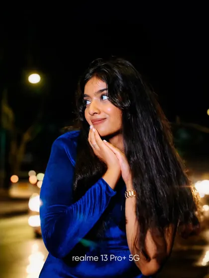 A night portrait with a focus on capturing a candid, happy moment. The blurred car lights in the background add a sense of motion and life to the scene.