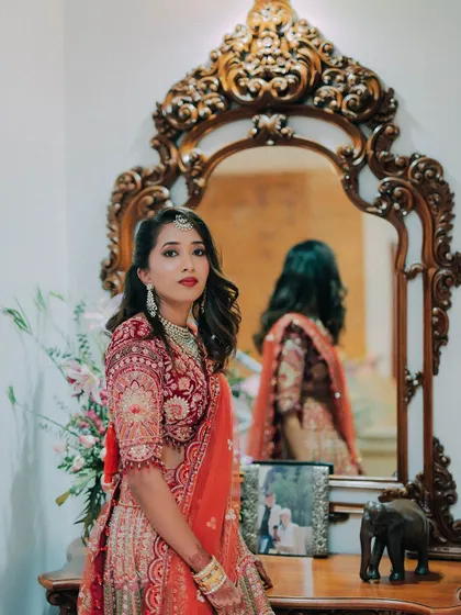 A beautiful portrait of a bride in her reception lehenga. The soft waves in her hair and the classic red lip create a look of timeless Hollywood glamour.