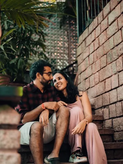 An intimate moment shared on a set of stairs, lit by a vintage lantern. The warm light and brick texture create a rustic and romantic pre-wedding photo.