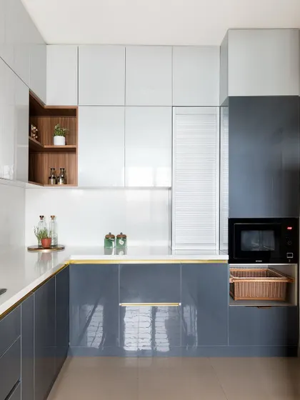 This kitchen is all about sleek functionality. I used a combination of glossy grey and white cabinets for a modern look. An open wooden niche and a dedicated space for the microwave and vegetable basket ensure everything is organized and within reach.