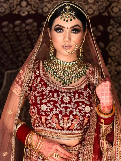 A full portrait of the bride wearing the green stone Kundan set. You can see how the necklace, maang tikka, and earrings come together for a complete look.