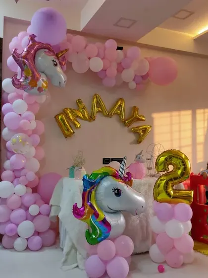 A magical unicorn-themed party for a second birthday. This setup includes a beautiful balloon arch in pastel pink and white, with large unicorn foil balloons to bring the fantasy to life.