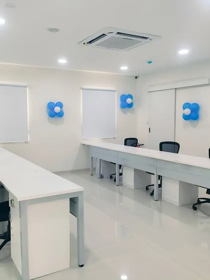 This training room setup at the TVS facility features long tables arranged for classroom-style learning. The neutral color palette and ample lighting create a professional and focused atmosphere.