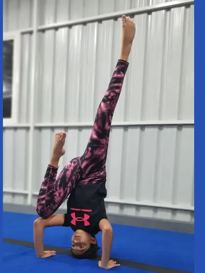This gymnast combines a headstand with a split, a beautiful pose that showcases both balance and an advanced level of flexibility.
