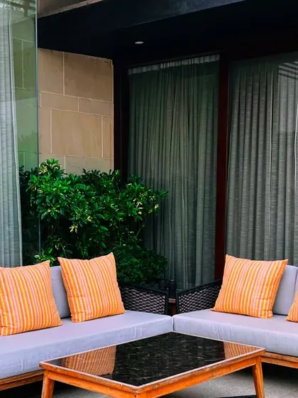 The patio seating area is positioned to integrate with the home's interior, with large glass doors creating a seamless indoor-outdoor flow. The surrounding greenery provides a sense of privacy and tranquility.