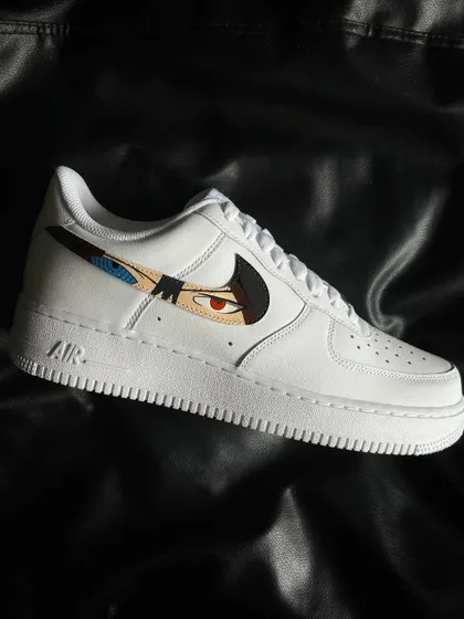 A side profile of the Sasuke custom sneaker, featuring his Rinnegan and Mangekyo Sharingan in the swoosh.