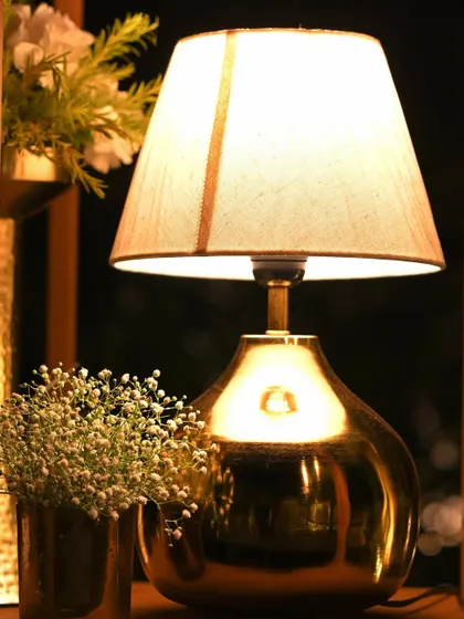 A close-up of a modern table lamp with a metallic gold base, paired with a vase of baby's breath. This shows how we mix modern and rustic elements for a unique look.