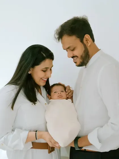 A beautiful family portrait, with the parents holding their little miracle. The coordinated white outfits create a clean, timeless look.