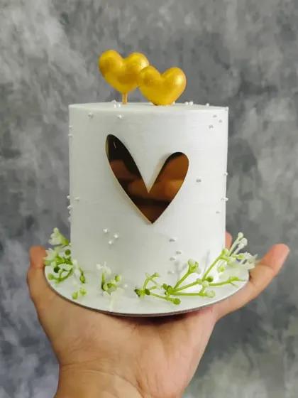 A mini white cake decorated with a gold heart and tiny flowers. Perfect for a small, intimate celebration.