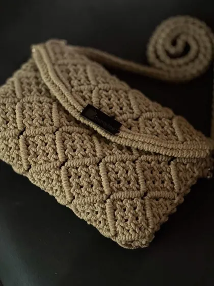 Another angle of the beige patterned clutch, with its strap neatly coiled.