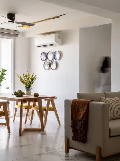 The dining area in our Jaipur penthouse project, featuring a minimalist wooden dining set and decorative wall plates. The design is clean, modern, and infused with subtle, artistic touches.