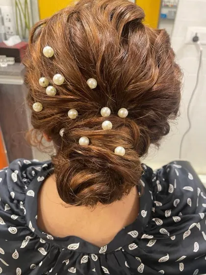 This messy bun is elevated with pearl accessories scattered throughout. It's a modern take on a classic updo, offering a chic and sophisticated look for any party.