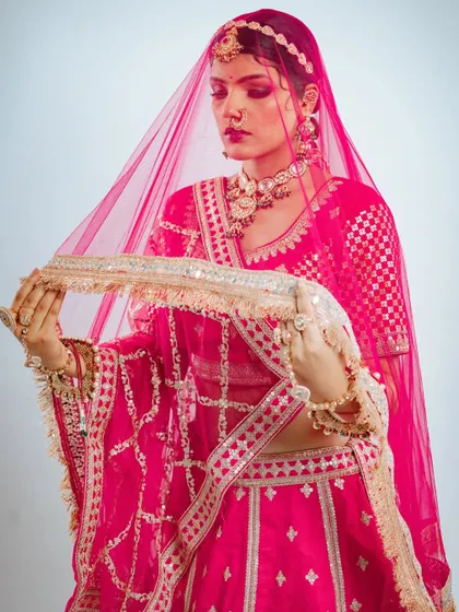 The delicate net dupatta with its beautiful border adds a layer of grace to the entire bridal look.