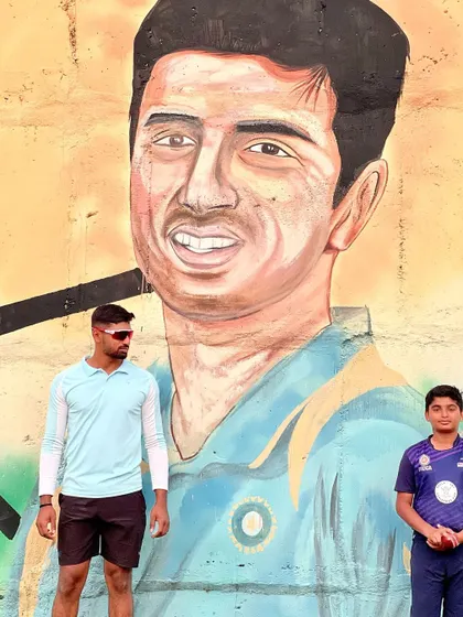 A coach stands with a young player in front of an inspirational mural. Our coaches are mentors who motivate our players to achieve their dreams.