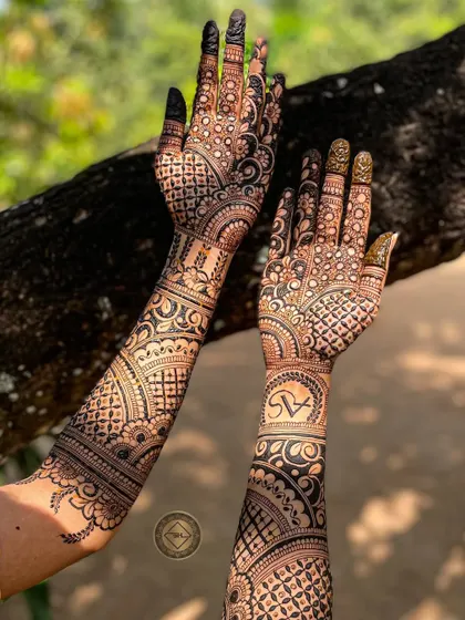 This full-arm bridal henna for Anuja features her and her partner's initials, S and A, elegantly placed within the design. The combination of bold patterns and fine details makes it stand out.