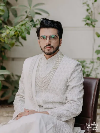 A classic, seated portrait of the groom, looking dapper and thoughtful in his elegant white sherwani.