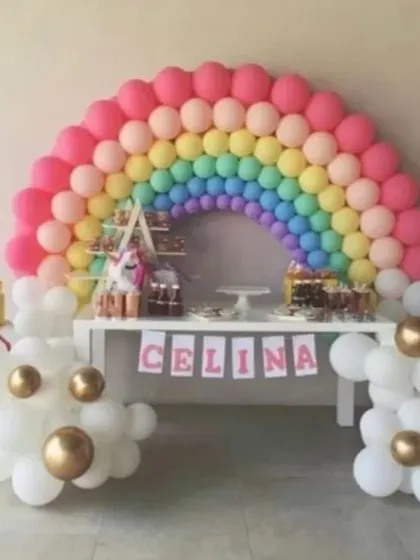 A beautiful rainbow balloon arch over a dessert table. This is a perfect, cheerful theme for any child's party.