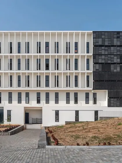 The facade of the housing project features a screen of vertical fins to provide shading, and a section of dark solar panels, expressing the building's sustainable design principles.