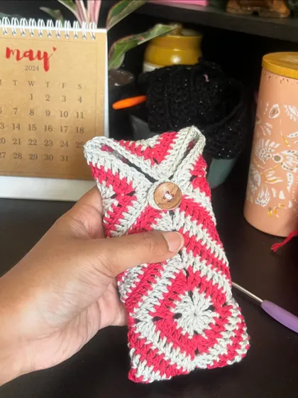 Holding the red and grey granny square pouch. The wooden button is a lovely natural detail.