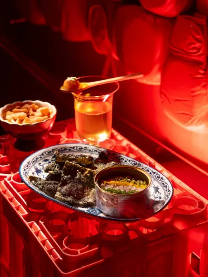 A food flat lay at Banng Bar, bathed in intense red light. The unusual setup on plastic crates and the monochromatic color scheme create a bold and modern aesthetic.