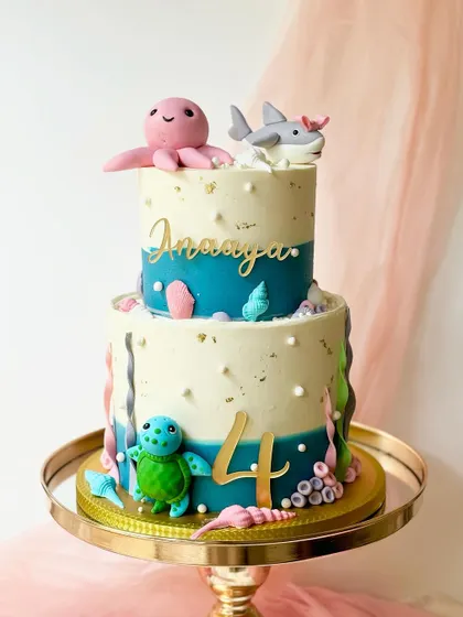 An underwater adventure on a two-tiered cake. This design features a friendly octopus, shark, and turtle, with gold leaf accents for a touch of sparkle.