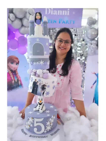A topsy-turvy Frozen-themed cake for Dianni's 5th birthday. The angled tiers create a fun, dynamic look, complete with a castle, Olaf, and an Elsa figurine. It's a magical cake for a little princess.