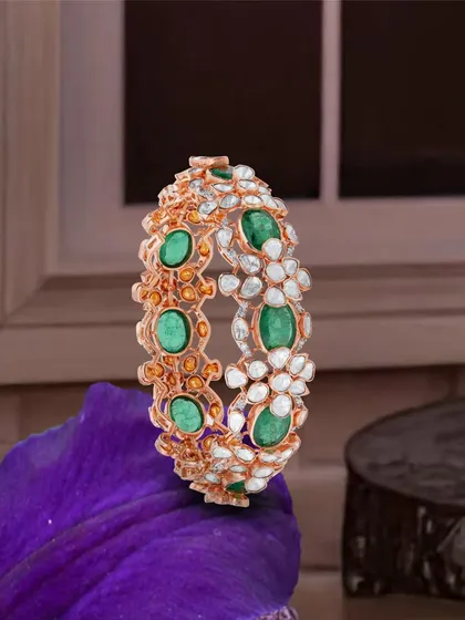 Emerald whispers and diamond lights, her pride shines in brilliance. This intricate kada combines uncut diamonds and vibrant emeralds in a floral design.