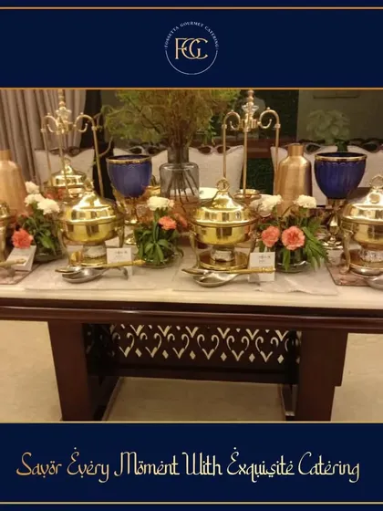 A sophisticated buffet setup on a marble-top table. The arrangement of polished brass chafing dishes and delicate flower bouquets is a perfect example of understated elegance for an intimate gathering.