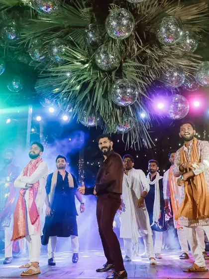 The groom takes center stage during his Sangeet performance. The backdrop of disco balls and dramatic stage lighting sets the perfect mood for a high-energy dance number.