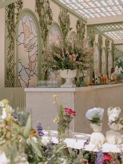 The main bar for the luncheon was set against a custom backdrop with stained-glass-effect panels and climbing ivy. A large urn of fresh flowers serves as a beautiful focal point.