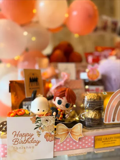 A close-up of the personalized 'Happy Birthday Tanishka' card, surrounded by whimsical figurines and treats. Every detail is designed to make a young girl's birthday feel truly magical.