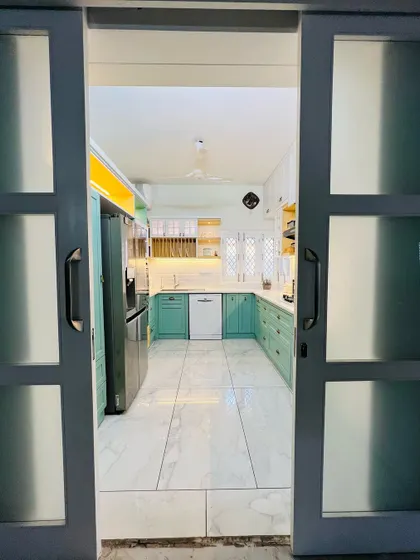A view into a bright and airy kitchen through a modern sliding barn door. The design uses light colors and a clean layout to create an inviting and spacious atmosphere.