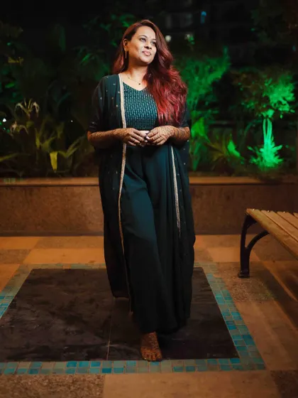 The bride's full-length portrait, showcasing her chic Mehendi outfit and the beautiful henna art.