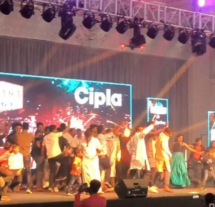 Guests dancing on stage at the Cipla event, with bright, colorful lighting creating a fun atmosphere.