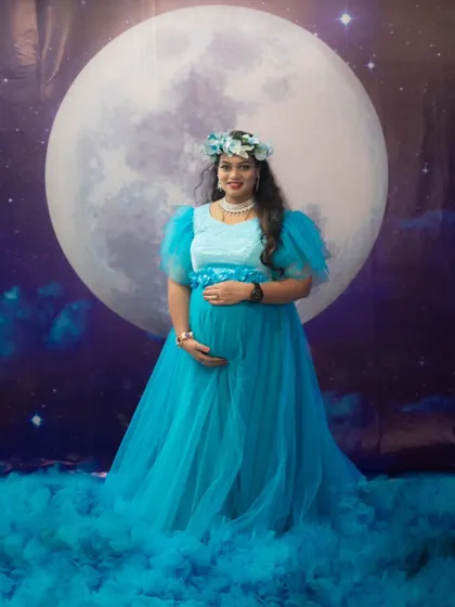 A celestial-themed maternity shoot with a moon backdrop, featuring our beautiful sky-blue ruffle gown for a magical look.