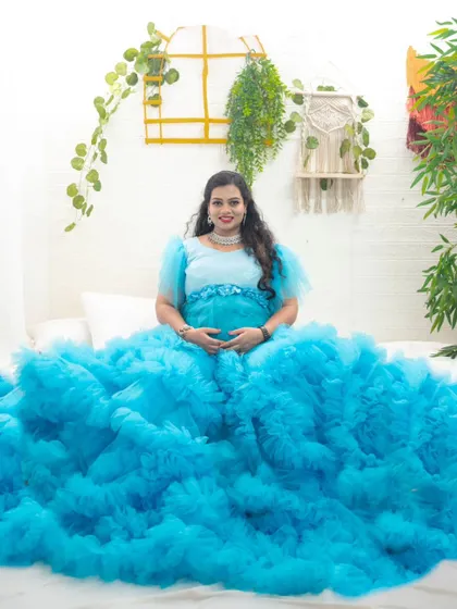 This dreamy blue ruffle gown creates a cloud-like effect, perfect for a soft and serene indoor maternity photoshoot.