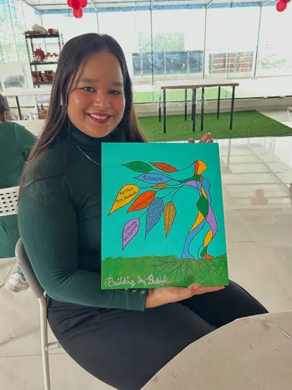 A participant proudly shows off her colorful abstract painting of a tree personified.