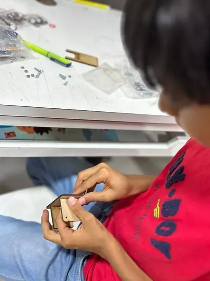 Summer time is build time. A student carefully assembles a wooden project during our hands-on electronics workshop, learning about construction and precision.