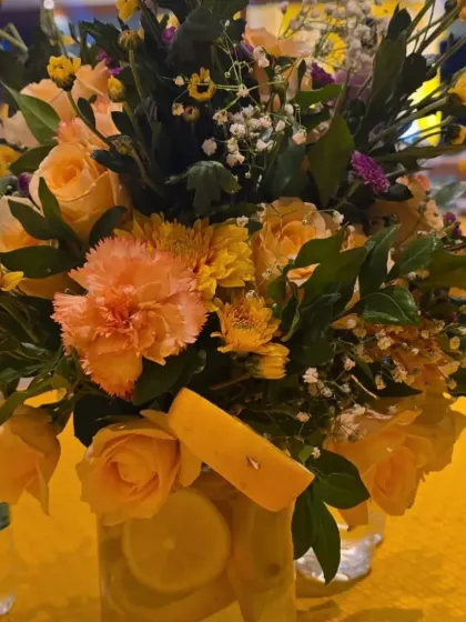A vibrant yellow floral centerpiece for a Haldi, incorporating fresh lemon slices in the vase for a unique and fragrant touch.
