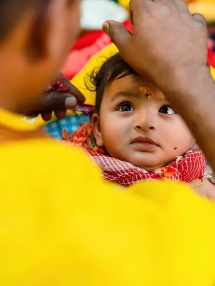 An intimate, over the shoulder shot of a baby receiving a blessing. This perspective makes you feel like you are part of the ceremony.