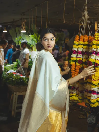 The colors and textures of a flower garland stall create a stunning backdrop for this portrait, capturing the essence of a traditional Indian market.