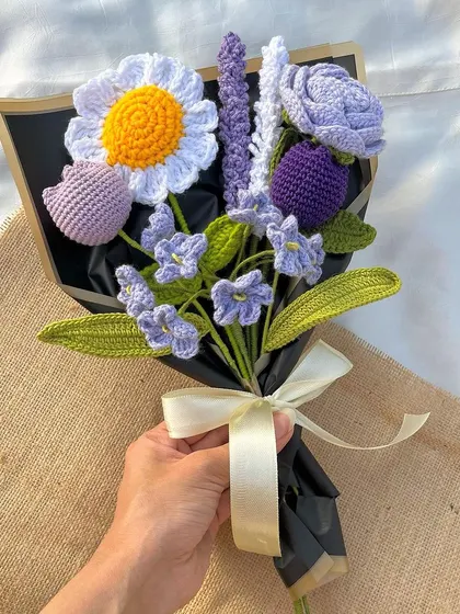 A hand holding our 'Lavender Love' bouquet, showing its size and intricate detail. It's a perfect handful of everlasting beauty.