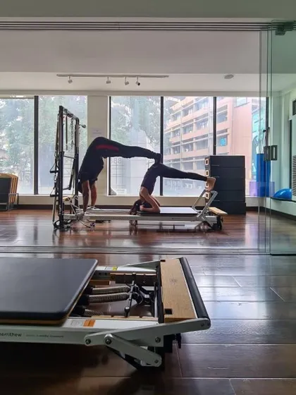 Partner work adds another layer of challenge and motivation. Here we see a combination of a handstand and a reformer headstand, showcasing balance and strength.