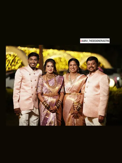 A perfect family portrait. The bride, groom, and parents all in coordinated pastel pink outfits for the reception.