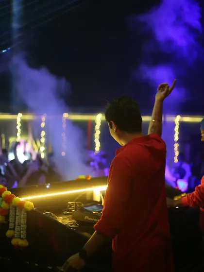 A view from behind, showing me raising a hand to the crowd while managing the mix. This demonstrates how I multitask to perform and entertain simultaneously.